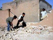 Boys remove rubble from the site of a mortar attack in Al-Najaf on May 23 (file photo) (epa)