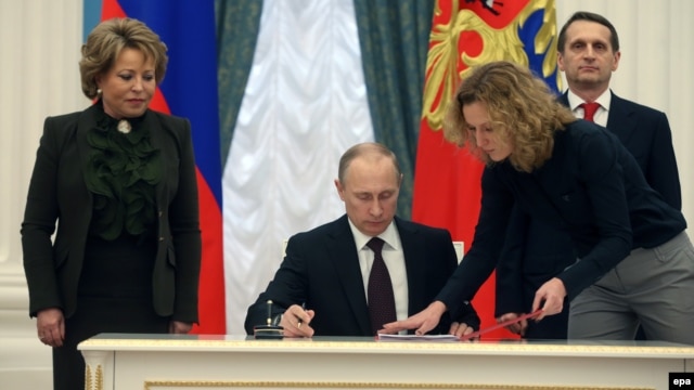 Russian President Vladimir Putin's (center) critics and civil-liberties activists have long accused the authorities of using counterterrorism and extremism laws to target the Kremlin's political opponents, and they say the new law threatens a dramatic escalation of this strategy.