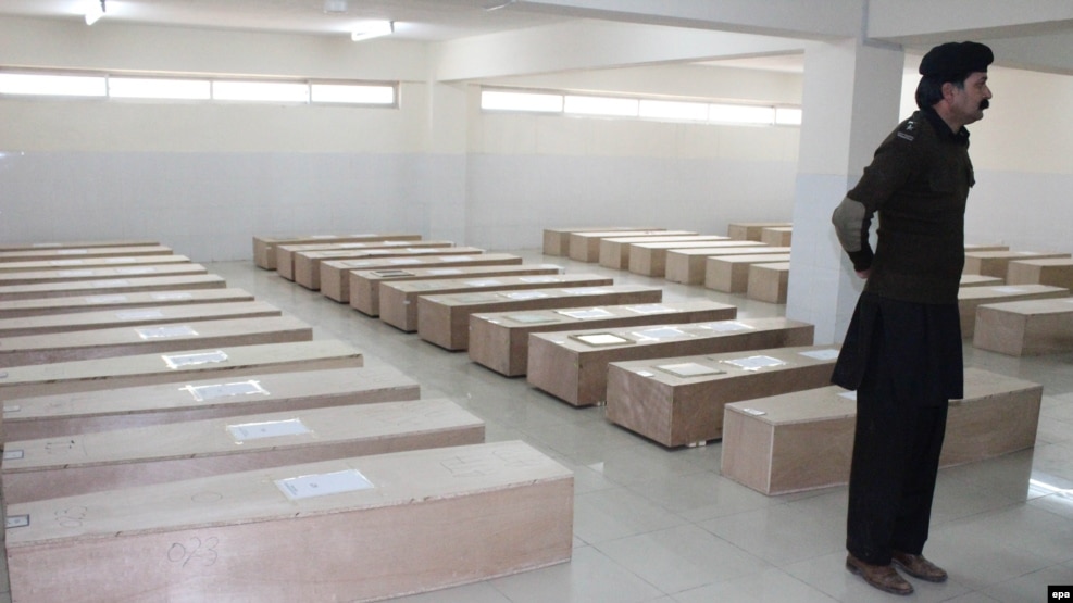A Pakistani security official stands guard beside coffins containing the remains of the victims of plane crash at a hospital in Abbottabad on December 8.