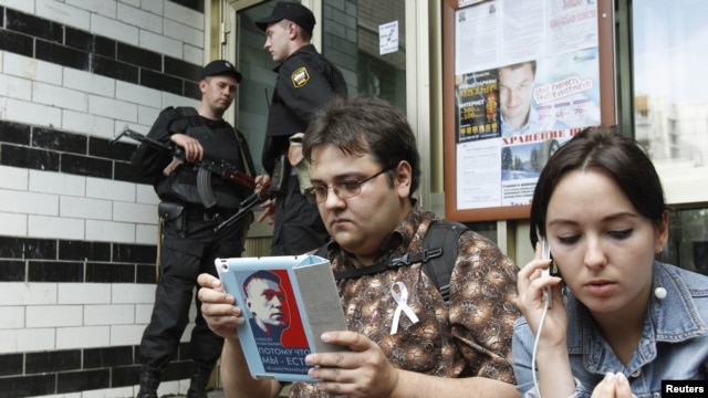 Russian security forces stand guard as an opposition supporter and Anna Veduta (right), a spokeswoman for opposition activist Aleksei Navalny, wait outside the entrance to the apartment block where Navalny lives in Moscow on June 11.