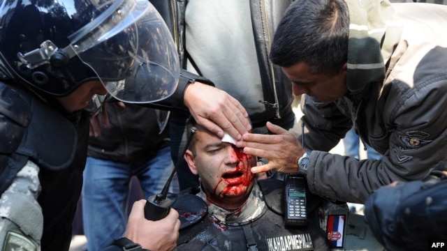 An injured riot police officer is cared for by colleagues in the center of Belgrade.