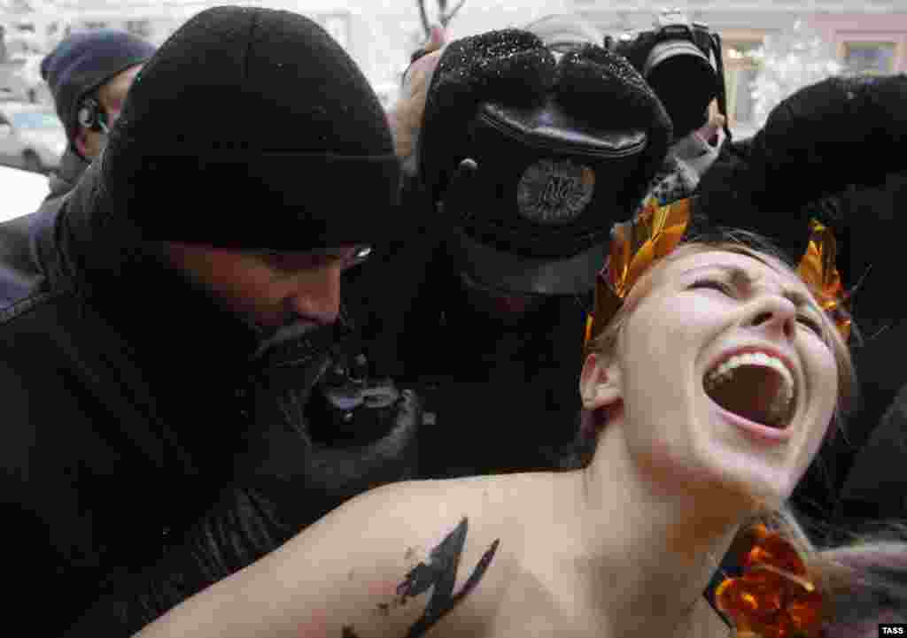 Ukrainian police officers detain a topless Femen activist protesting against the untenability of the newly elected parliament in Kyiv. (ITAR-TASS/Maria Frolova)