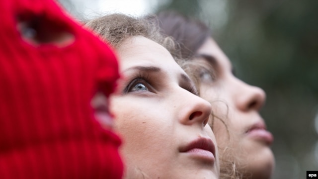 Nadezhda Tolokonnikova (right) and Maria Alyokhina (center), and a masked Pussy Riot activist are pictured during a news conference held outside a hotel in a park in Sochi on February 20.