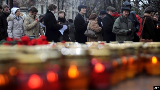 People wait for their turn to lay flowers and place candles at a memorial to the victims of Soviet-era political repression on Lubyanka Square in Moscow.