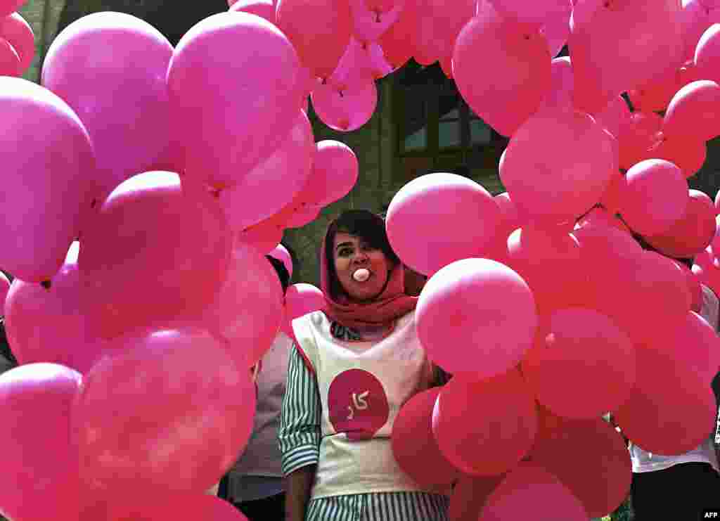 An Afghan volunteer blows a chewing-gum bubble as she prepares balloons for the "We Believe in Ballons" event, an art project promoting peace in Kabul on May 25. (AFP/Massoud Hossaini)