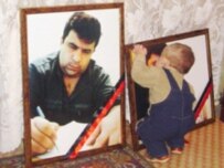 The son of the murdered Azerbaijani journalist Elmar Husseynov kisses his father's portrait (RFE/RL)