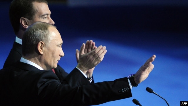 Dmitry Medvedev (back) and Vladimir Putin wave to delegates at a United Russia congress in Moscow on November 27.