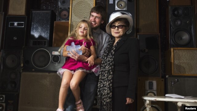 Pyotr Verzilov, husband of convicted Pussy Riot band member Nadezhda Tolokonnikova, holds his daughter Gera as he accepts the Lennon Ono Grant for Peace from Yoko Ono in New York on September 21.