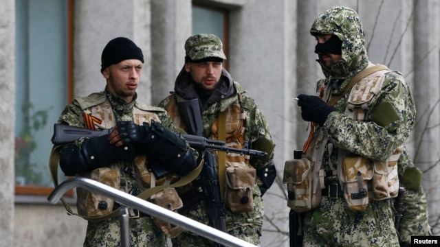 Pro-Russian gunmen stand guard outside the mayor's office in Slovyansk, Ukraine, on April 14. Can Kyiv prove some are Russian servicemen?
