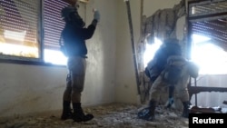 UN experts, wearing gas masks, inspect one of the sites of an alleged chemical weapons attack in a Damascus suburb last month.