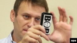 Russian opposition leader Aleksei Navalny takes pictures with his mobile phone decorated with a sticker depicting Russia's President Vladimir Putin inside the middle letter of the Russian word 'BOP' ("thief") in a courtroom in Kirov on October 16.