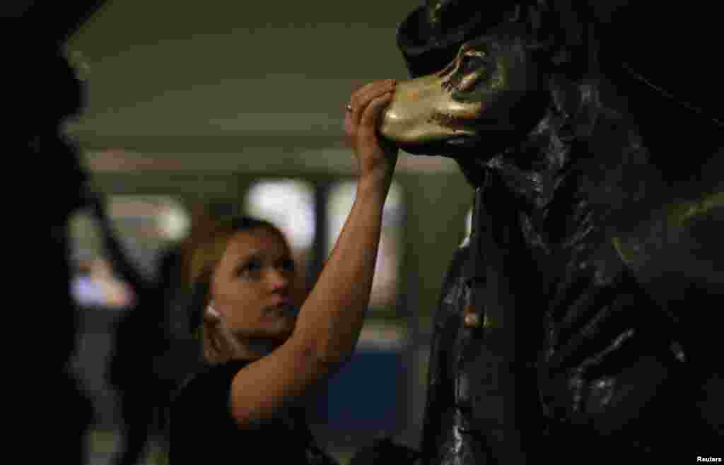 A woman touches the nose of the so-called "lucky dog" statue at the Ploshchad Revolyutsii station.