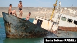 Мальчики прыгают в воду со старой лодки в поселке Баутино в Каспийском море. 3 мая 2013 года.