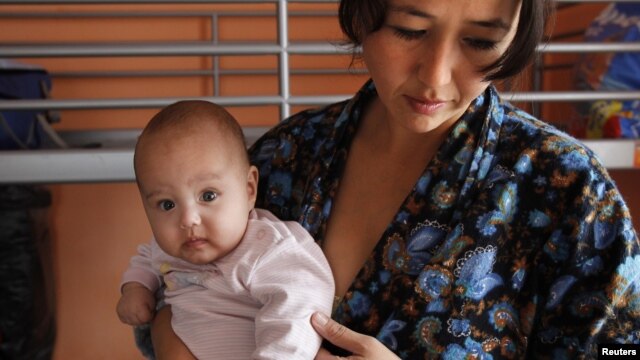 A single Tajik woman holds one of her twins in a shelter for women in crisis where she and other single women live outside Moscow.