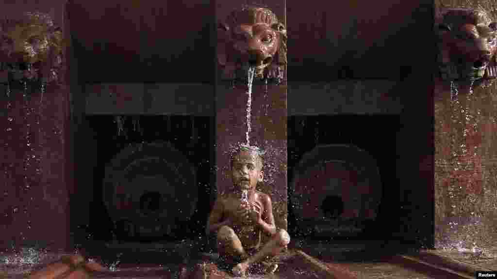 An Indian boy cools himself off as he sits under a fountain on a hot summer day in New Delhi on May 31. (Reuters/Adnan Abidi)