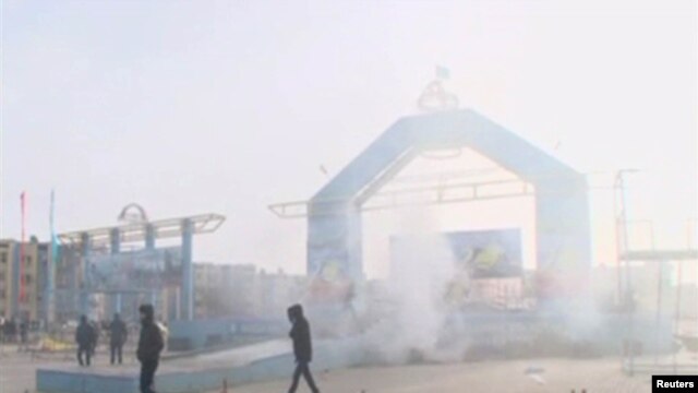 People walk past a destroyed stage in Zhanaozen in this still image taken from a video acquired by Reuters on December 16.