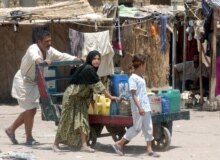 Iraq -- An Iraqi man pushes a hand-cart at a refugee camp for Iraqi families, in Baghdad, 29Jun2006