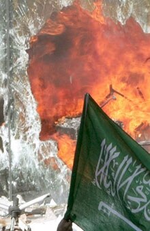 Lebanon – Danish cartoons of Prophet Muhammad / Anti-Western sentiment – An Islamic flag seen through the shattered window of the burning Danish consulate in Beirut, Lebanon, 5 February 2006. (Width: 220; vertical photo.) Source: EPA.