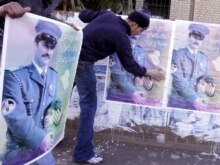 Iraq -- An Iraqi man places posters on a hoarding to highlight national reconciliation in Baghdad, 15Jan2007