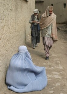 Afghanistan -- A burqa-clad Afghan woman begs on a street in Kabul as world observe International Women's Day, 8 Mar. 2006