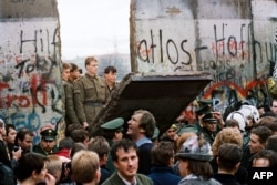 Жителі Західного Берліна збираються перед Берлінською стіною 11 листопада 1989 року, спостерігаючи, як східнонімецькі прикордонники руйнують частину стіни, щоб відкрити новий пункт пропуску між Східним і Західним Берліном