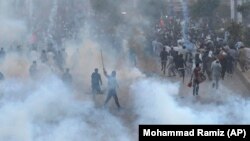 PTI supporters run for cover after police fire a tear gas shell during a protest to condemn an assassination attempt on their leader, former Prime Minister Imran Khan, in Rawalpindi on November 4. 