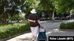 Gurulós bevásárlótáskával sétál egy nő a zuglói Bosnyák téri piac közelében, Budapesten 2022. július 2-án