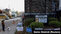 Muškarac sa psom prolazi pored plakata za kandidate u Picburgu, na izborima u Pensilvaniji, 8. novembar 2022.