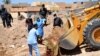 Iraqi officers and forensics team personnel dig at a site believed to be a mass grave in Ramadi, April 19, 2016