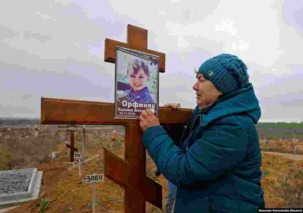 Iryna Orfinyak at the grave of her granddaughter, Veronika, in the Starokrymske cemetery in the northwest of Mariupol on November 9. The child was killed alongside her father when a mortar round landed among a huddle of people cooking outside during the Russian siege of the city. &nbsp;