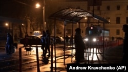 People wait at a tram stop during a blackout in Kyiv.