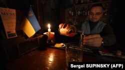 A bartender pours a drink by candlelight during a power cut at a bar in the center of Ukrainian capital of Kyiv. 