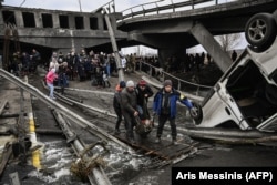 Люди переходят разрушенный мост во время эвакуации из города Ирпень, к северо-западу от Киева, во время сильных обстрелов и бомбардировок 5 марта 2022 года
