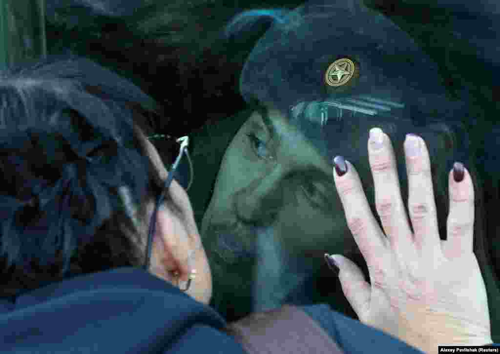 A conscript kisses the window of a train carriage as he says goodbye to family members at a local railway station during departure for the garrisons, in Sevastopol, Crimea.