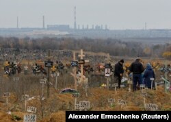 Люди посещают кладбище во временно оккупированном поселке Старый Крым вблизи Мариуполя. 9 ноября 2022 года