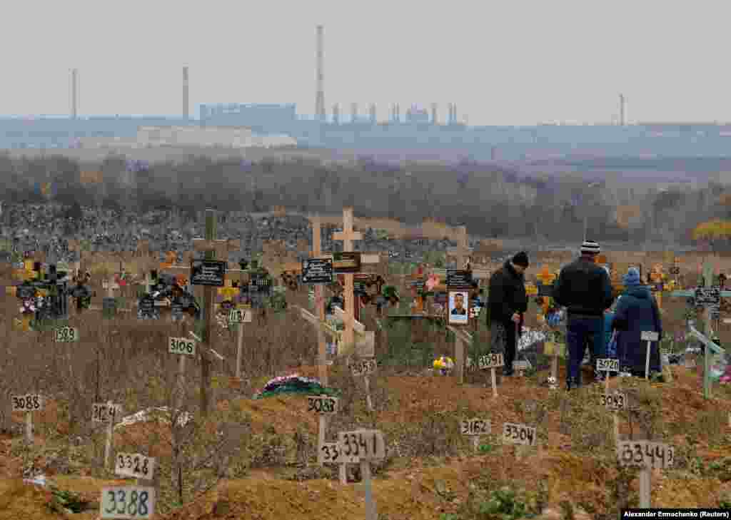 Priveghi la un mormânt din cimitirul din Mariupol pe 9 noiembrie. Se crede că zeci de mii de oameni au murit în timpul asediului de aproape trei luni al orașului. În acea perioadă, civilii au trăit fără energie electrică și apă, fiind bombardați constant. &nbsp;