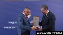 Serbian President Aleksandar Vucic presents a medal to a policemen from the north of Kosovo who refused to implement a decision by Pristina's government on the reregistration of car-license plates.