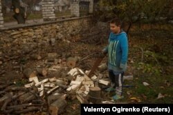 Egy fiú készül tűzifát fűrészelni az orosz katonai támadások során megrongálódott ház fűtéséhez Oszokorivka faluban, az ukrajnai Herszoni területen 2022. november 9-én