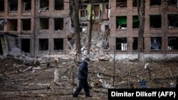 Мужчина идет перед разрушенным зданием после ракетного обстрела Россией города Васильков под Киевом. 27 февраля 2022 года.