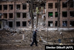 Мужчина идет перед разрушенным зданием после ракетного обстрела Россией города Васильков под Киевом, 27 февраля 2022 года