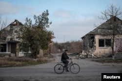 Un localnic surprins în fața unor case distruse în satul Arkanhelske din regiunea Herson, Ucraina, 8 noiembrie 2022.