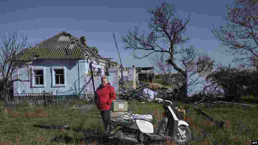 Egy nő áll háza mellett egy&nbsp;Mikolajiv melletti faluban. Az épület az orosz támadások során&nbsp; megrongálódott.