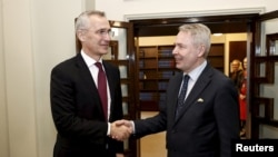 NATO Secretary-General Jens Stoltenberg (left) and Finnish Foreign Minister Pekka Haavisto shake hands at the Finnish parliament in Helsinki on February 28.