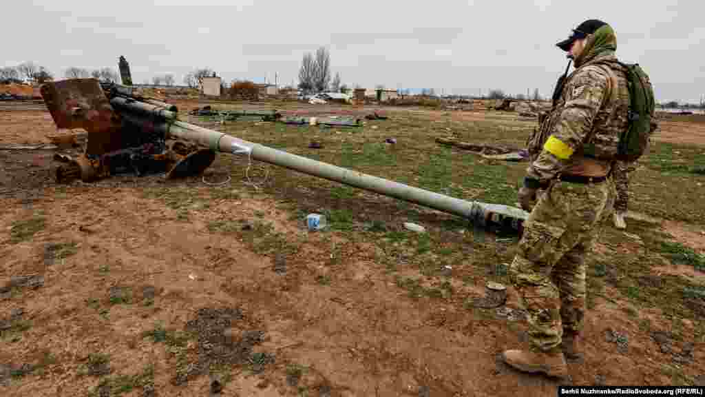 Військовий ЗСУ дивиться на&nbsp;знищену російську воєнну техніку неподалік&nbsp;аеропорту &laquo;Херсон&raquo; у Чорнобаївці, 13 листопада 2022 року