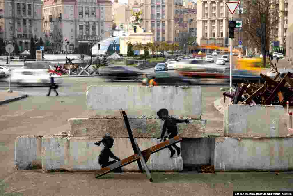 Egy másik graffiti Banksy stílusában: a páncélozott harckocsik feltartóztatására használt sünökön hintáznak a betondarabra festett gyerekek