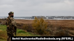 Украинский военный смотрит на разрушенный Антоновский мост. Херсонщина, 13 ноября 2022 года