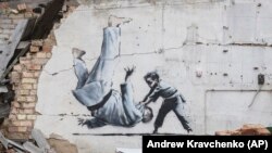 O posibilă lucrare a artistului britanic stradal Banksy pe zidul unei clădiri distruse de lupte la Borodianka, regiunea Kiev, 13 noiembrie 2022.