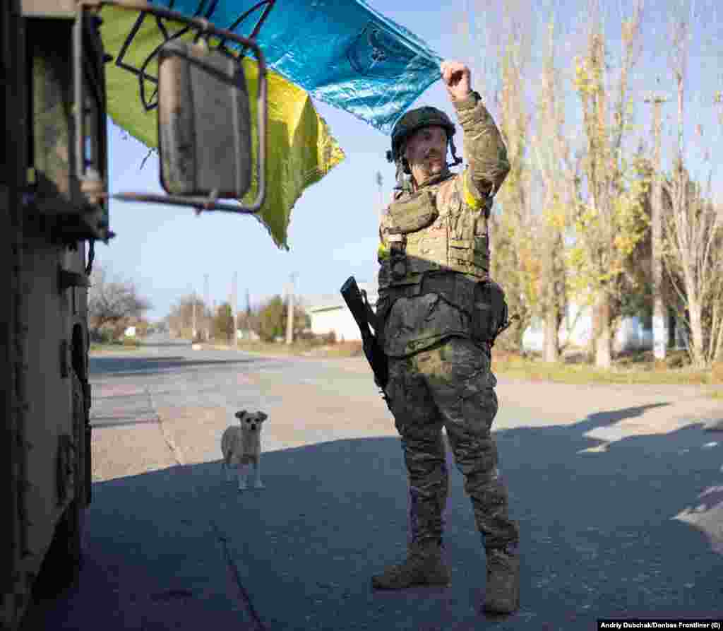 A soldier holds a weathered Ukrainian flag as the sun begins to set on the freshly recaptured town. Snihurivka&nbsp;had been occupied by Russian forces since March.&nbsp;