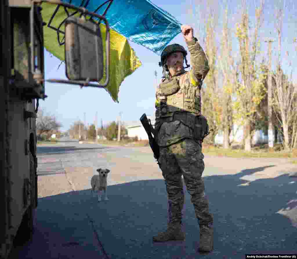 Un soldat arborează un steag ucrainean în timp ce soarele începe să apună peste orașul proaspăt recucerit. Snihurivka a fost sub ocupația forțelor rusești din luna martie.&nbsp;