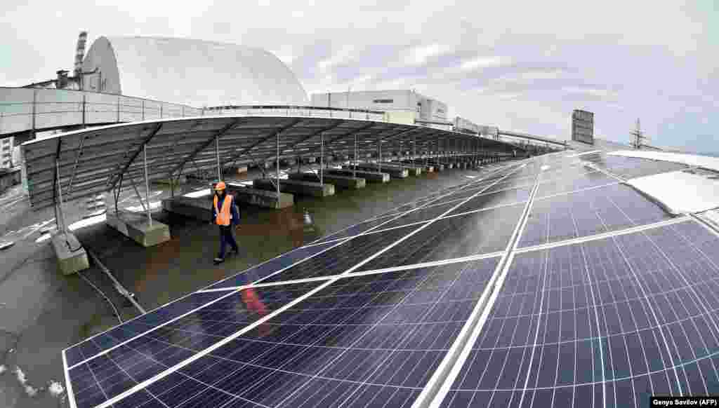 A worker strolls between the solar arrays. The company was quoted in January as saying it expects the $1.2 million project to begin operation &quot;within weeks.&quot; Despite the gloomy weather in these photos, Chernobyl reportedly shares the same number of sunlight hours as southern Germany.